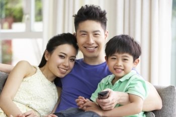 Chinese Family Sitting And Watching TV On Sofa Together