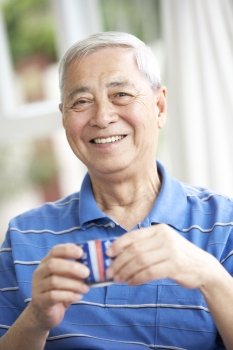 Senior Chinese Man Drinking Tea On Sofa At Home