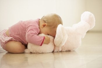 Baby Girl Cuddling Pink Teddy Bear At Home