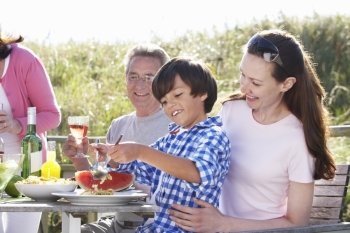 Mother With Son And Grandfather Enjoying Outdoor Barbeque