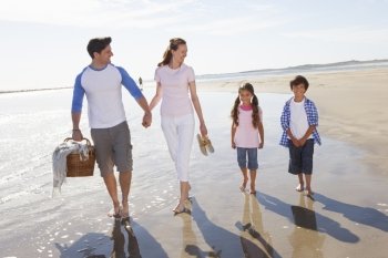 Family Walking Along Beach With Picnic Basket