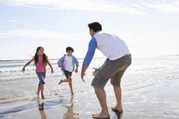 Children Running Towards Father On Beach