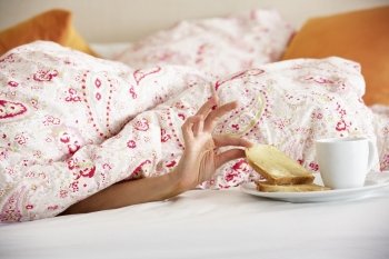 Woman's Hand Reaching From Under Duvet For Breakfast
