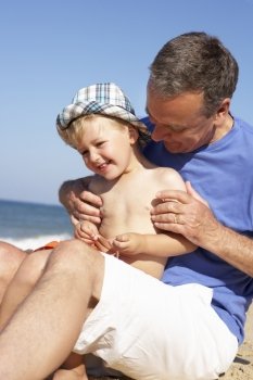 Grandfather And Grandson Sitting On Beach
