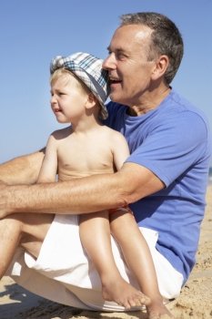 Grandfather And Grandson Sitting On Beach