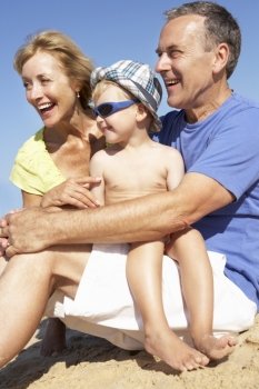 Grandparents And Grandson Sitting On Beach