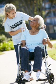 Teenage Volunteer Pushing Senior Woman In Wheelchair