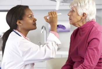 Doctor Examining Senior Female Patient's Eyes