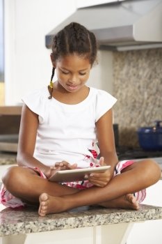 Girl Sitting On Kitchen Counter With Digital Tablet