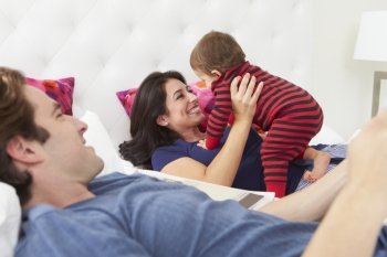 Family Relaxing In Bed With Young Son