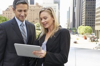 Businessman And Businesswoman Using Digital Tablet Outside