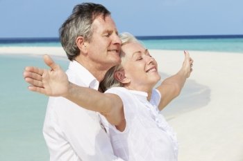 Senior Couple Withs Arms Outstretched On Beautiful Beach