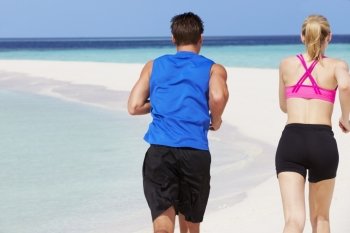 Rear View Of Couple Running On Beautiful Beach