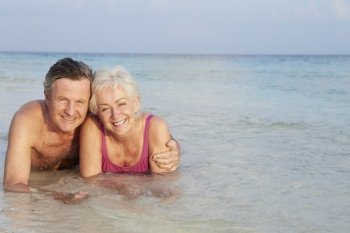 Romantic Senior Couple Lying In Sea On Beach Holiday