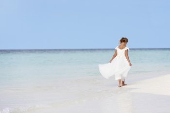 Young Girl In Bridesmaid Dress Walking On Beautiful Beach