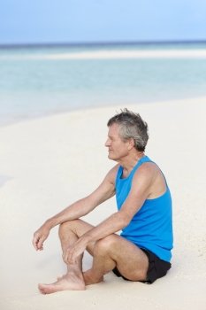Senior Man In Sports Clothing Relaxing On Beautiful Beach