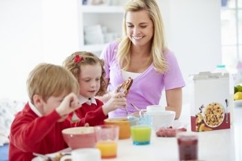 Mother And Children Having Breakfast In Kitchen Together