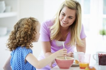 Mother And Daughter Having Breakfast In Kitchen Together