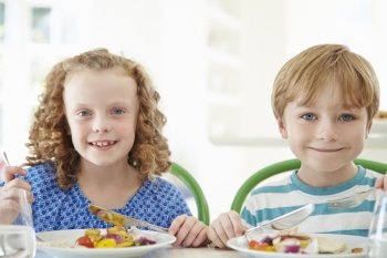 Two Children Eating Meal At Home Together