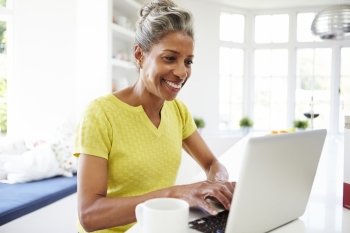 African American Woman Using Laptop In Kitchen At Home