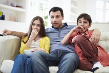 Father And Children Sitting On Sofa Watching TV Together