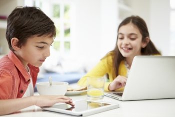 Children With Digital Tablet And Laptop At Breakfast