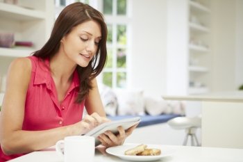 Hispanic Woman Using Digital Tablet In Kitchen At Home