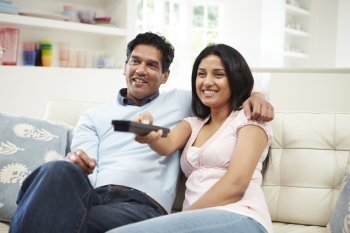 Indian Couple Sitting On Sofa Watching TV Together