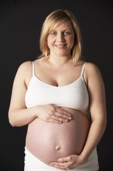 Portrait Of Pregnant Woman Wearing White On Black Background
