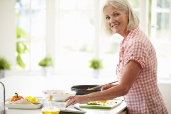 Middle Aged Woman Following Recipe On Digital Tablet