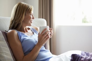 Middle Aged Relaxing In Bed With Hot Drink