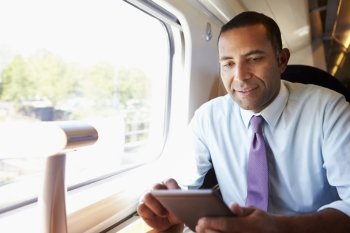 Businessman Commuting On Train Reading E Book