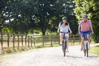 Asian Couple On Cycle Ride In Countryside