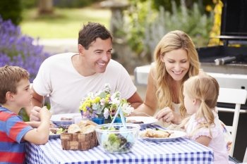 Family Enjoying Outdoor Meal In Garden