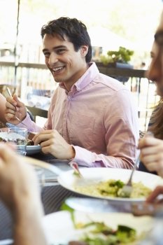 Man Enjoying Meal At Outdoor Restaurant With Friends