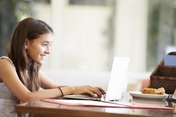 Teenage Girl Using Laptop On Desk At Home