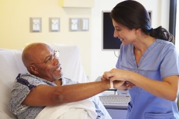 Nurse Putting Wristband On Senior Male Patient In Hospital