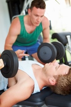 Two Young Men Training In Gym With Weights