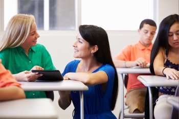 Teacher Helping Female High School Student In Classroom