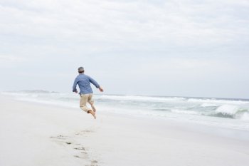 Senior man running and jumping on beach