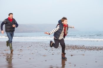 Father And Son Running On Winter Beach