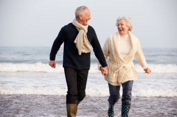Senior Couple Running Along Winter Beach