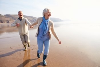 Senior Couple Running Along Winter Beach