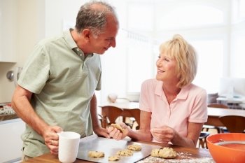 Senior Woman With Husband Baking Cookies In Kitchen