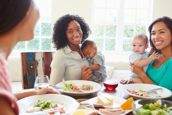 Female Friends With Babies Enjoying Meal At Home Together