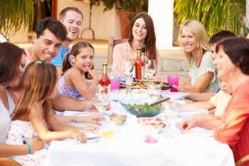 Large Family Group Enjoying Meal On Terrace Together