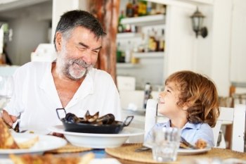 Grandfather And Grandson Enjoying Meal In Restaurant