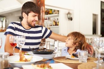 Father And Son Enjoying Meal In Restaurant