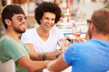 Group Of Male Friends Enjoying Meal In Outdoor Restaurant