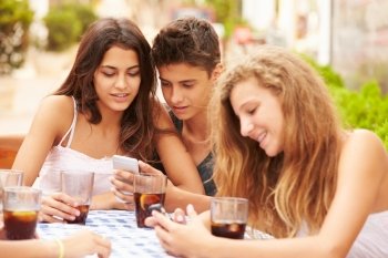 Group Of Teenage Friends Using Mobile Phone Sitting At Caf‚